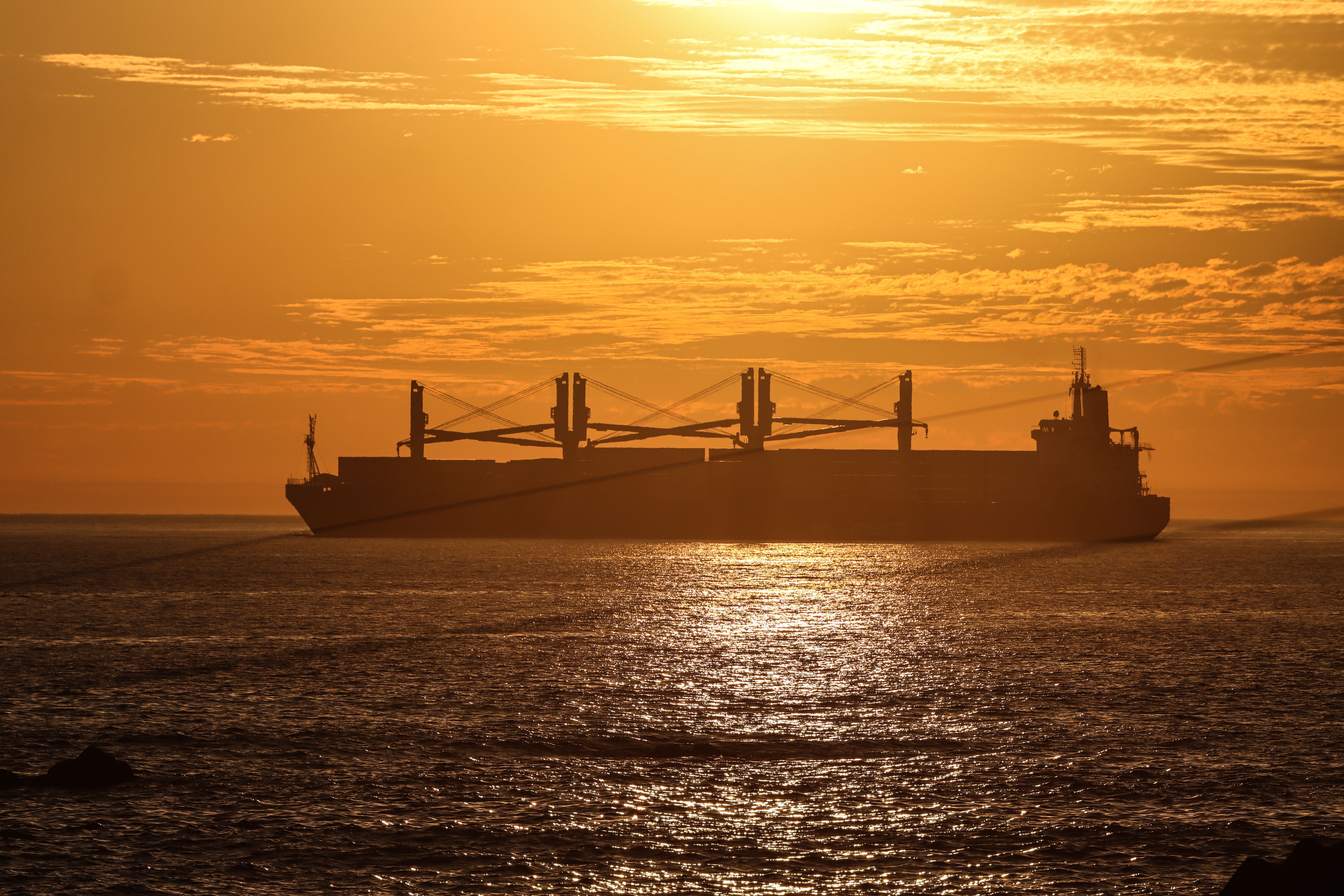 Bulk carrier silhouetted against the sunset at sea