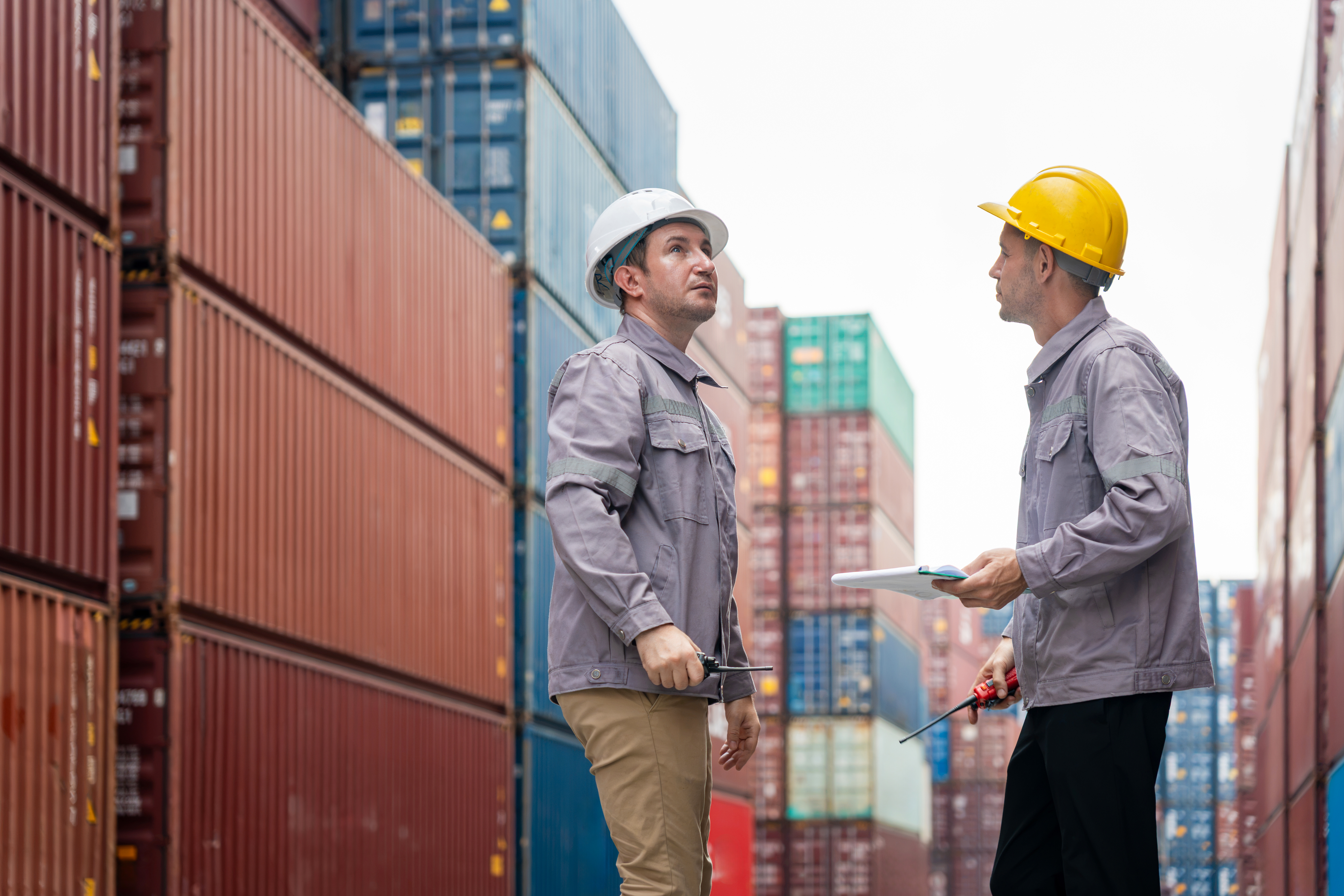 Two terminal engineers reviewing a checklist among stacked containers